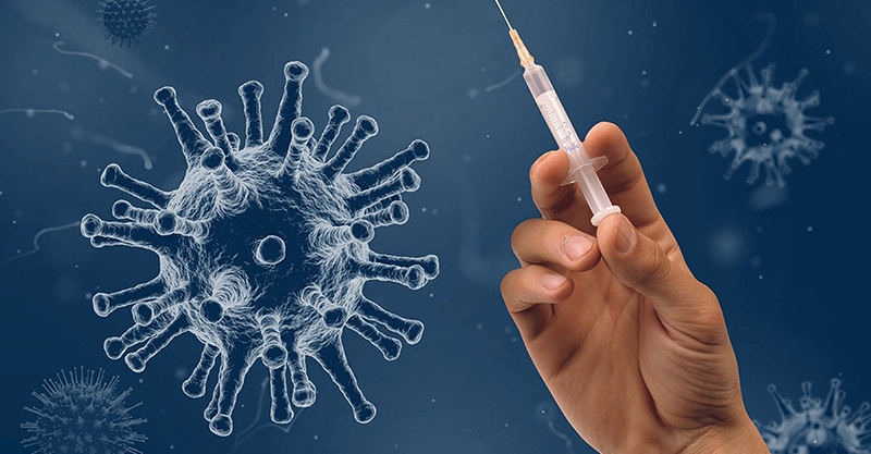 Eine Hand mit einer Spritze. Im Hintergrund sind Viren abgebildet.